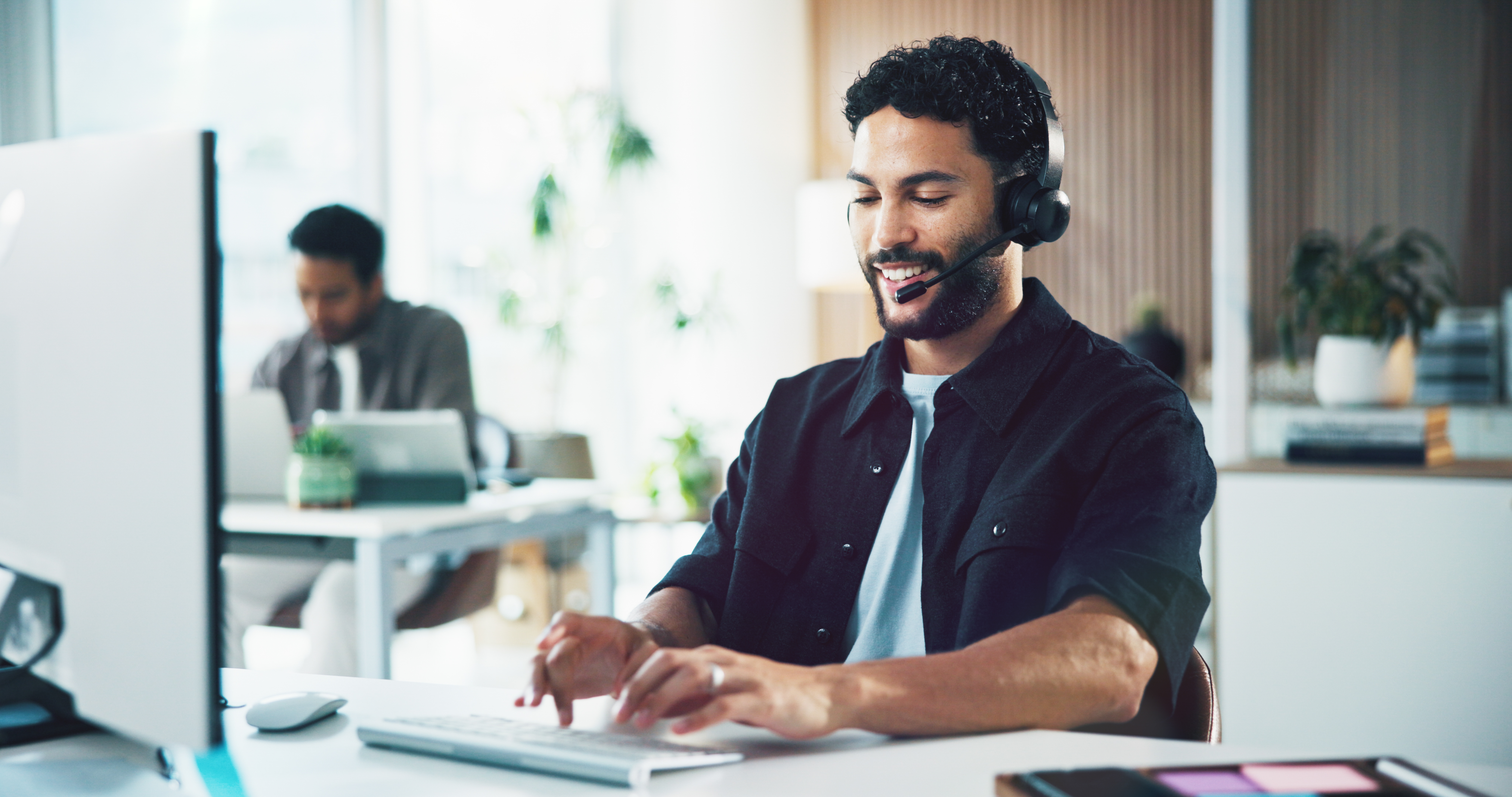 Call center, computer and man in office, typing for customer service and headset for communication. Person, employee and consultant in workplace, pc or discussion for application or online assistance